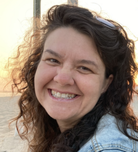 Charity smiles widely in close up photo with sunsetting behind